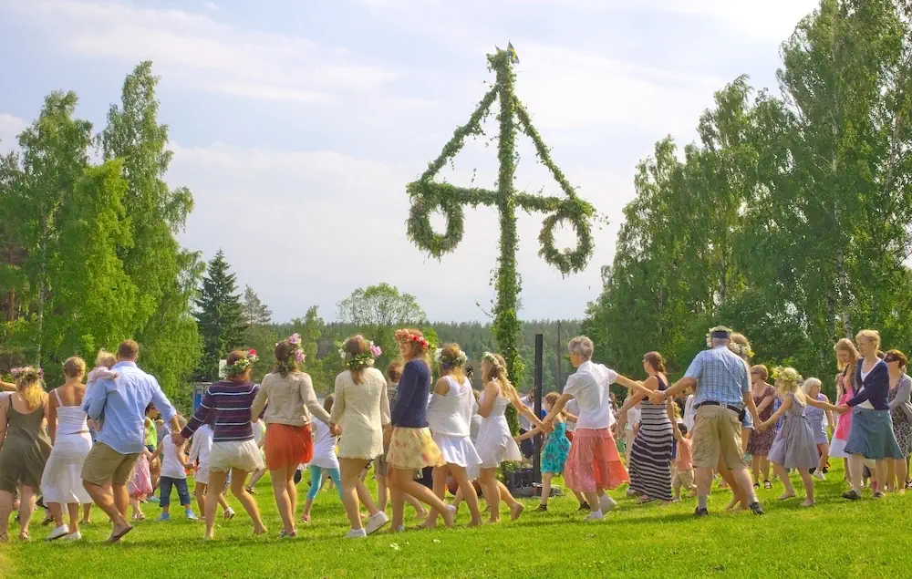 Svenskt midsommarfirande med dans runt majstång